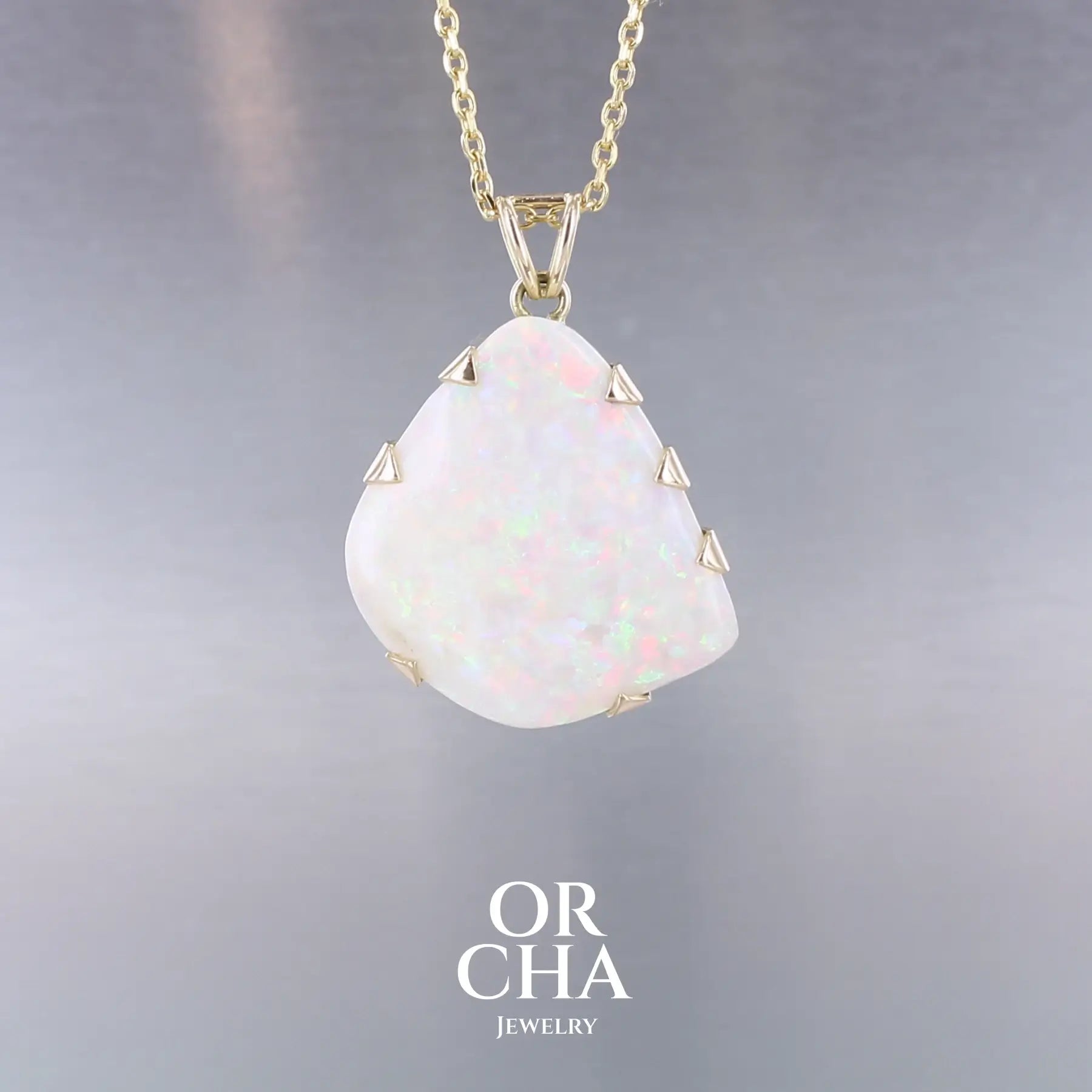 Pendentif pour femme en or jaune 18k serti d'une opale blanche de 17 carats aux feux multicolores. Pierre naturelle cabochon de forme irrégulière sertis  de griffes. A noter: présence de roche mère de couleur crème au dos de la pierre. Bijoux unique, éthique et durable présenté dans un coffret de notre marque, prêt à offrir. Livraison offerte, certificat d'authenticité, service client

