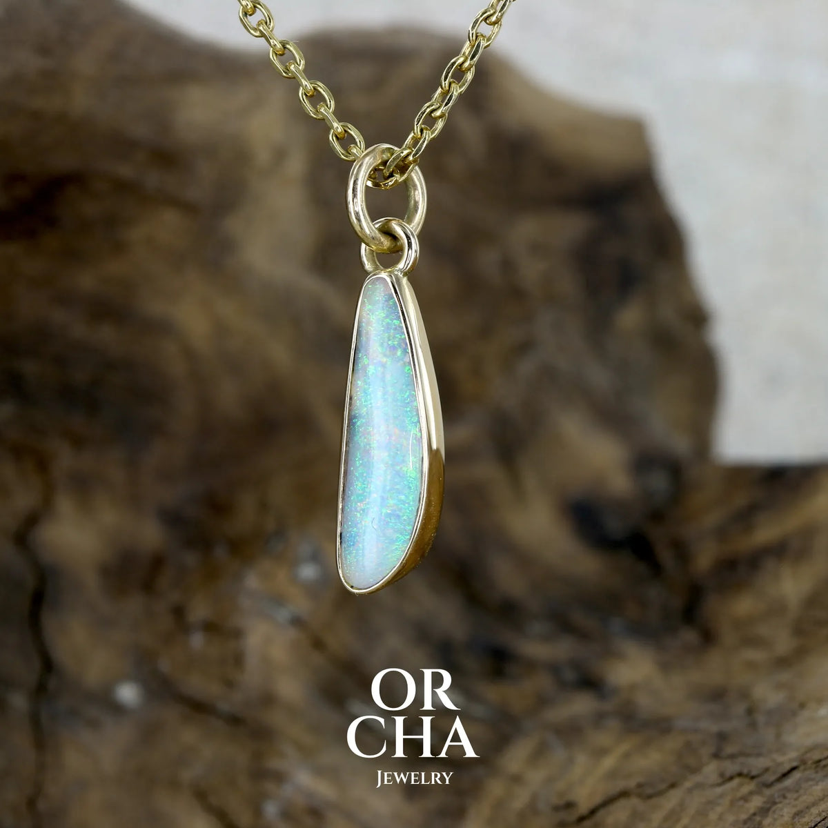 Pendentif pour femme en or jaune massif 18k serti d'une opale cristal aux feux étoilés multicolores à dominantes vert turquoises. Cabochon de 1 carat taille en forme de goutte de qualité transparente. Bijou unique réalisé par Orchajewelry