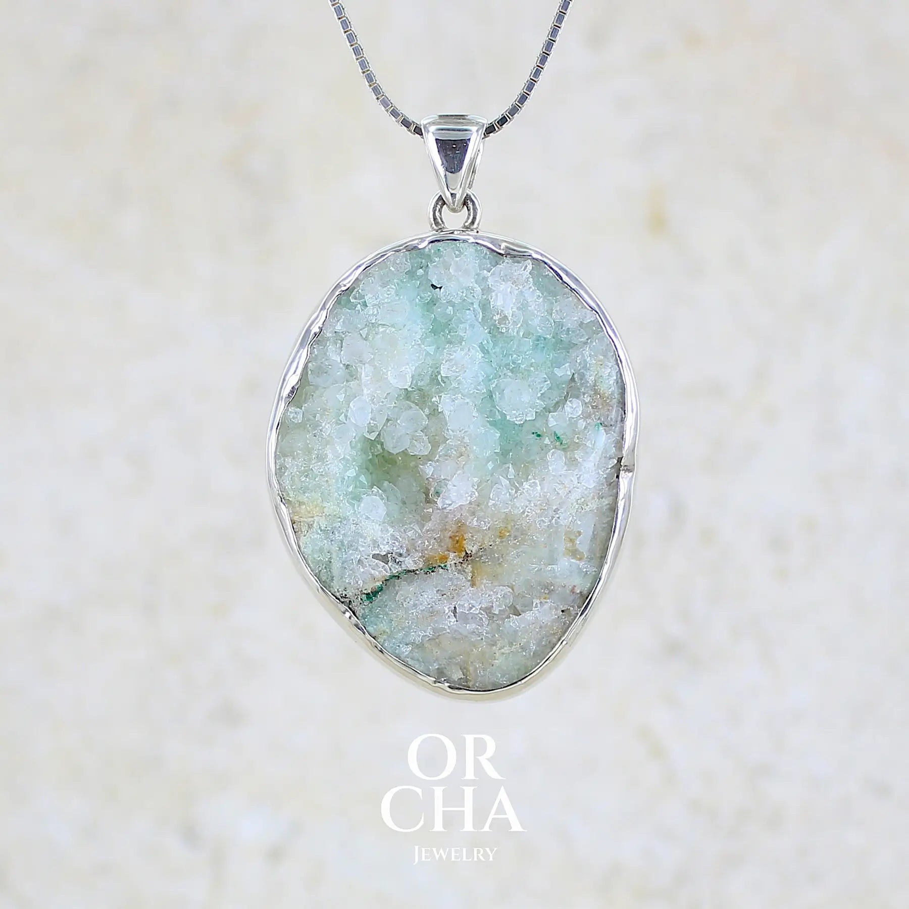 Pendentif en argent massif serti d'un magnifique gemsilica druze: chrysocolle silicifiée recouverte de fins cristaux de quartz scintillant. Pierre de qualité opaque brute de forme ovale. Pierre naturelle originaire du Mexique de couleur verte bleutée claire.
