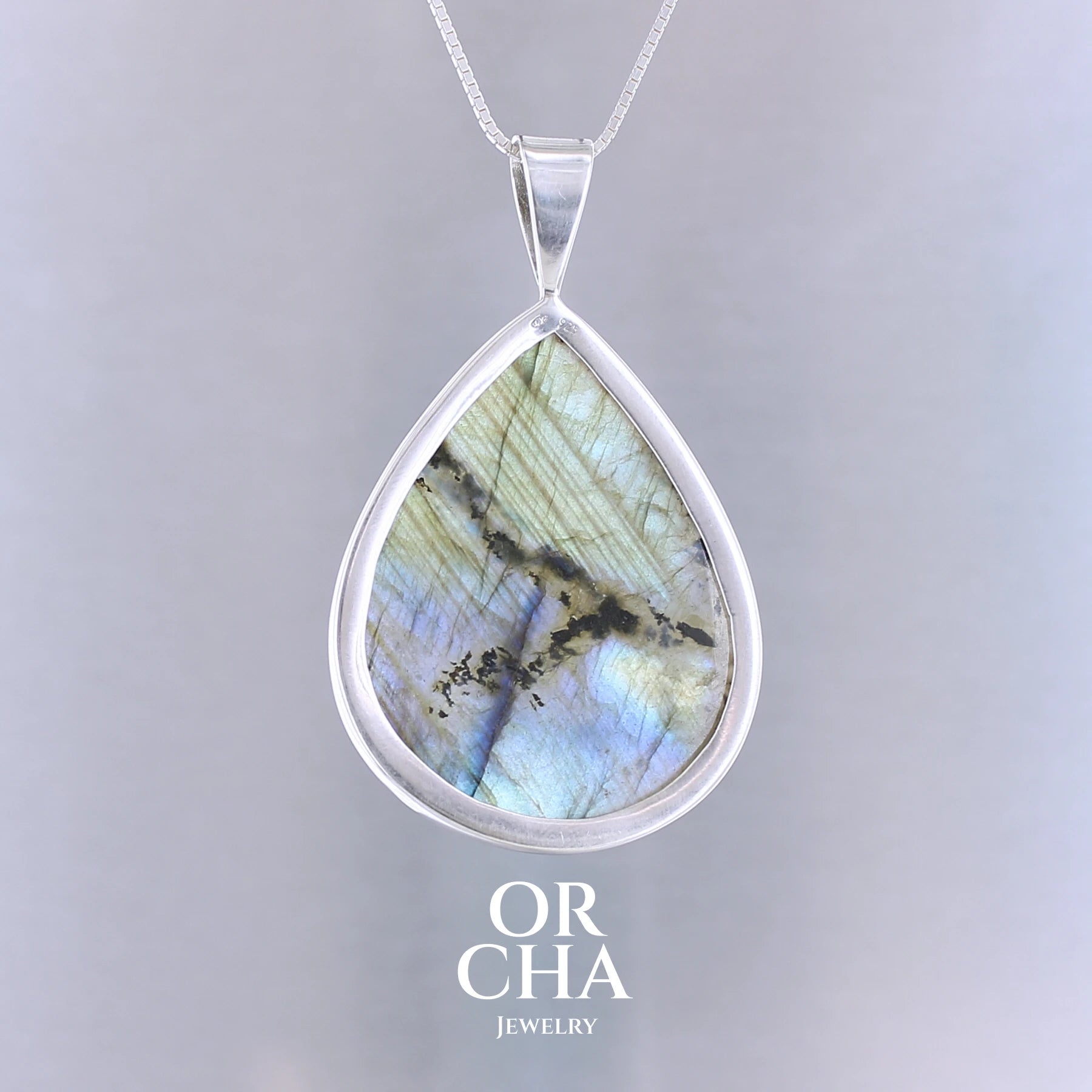 Pendentif pour femme en argent massif sertie d'une labradorite aux reflets bleus, bronzes et or selon la lumière. Pierre facettée naturelle translucide présentant des inclusions fréquents sur ce type de pierre. Bijoux unique, éthique et durable présenté dans un coffret de notre marque, prêt à offrir. Livraison offerte, certificat d'authenticité, service client.
