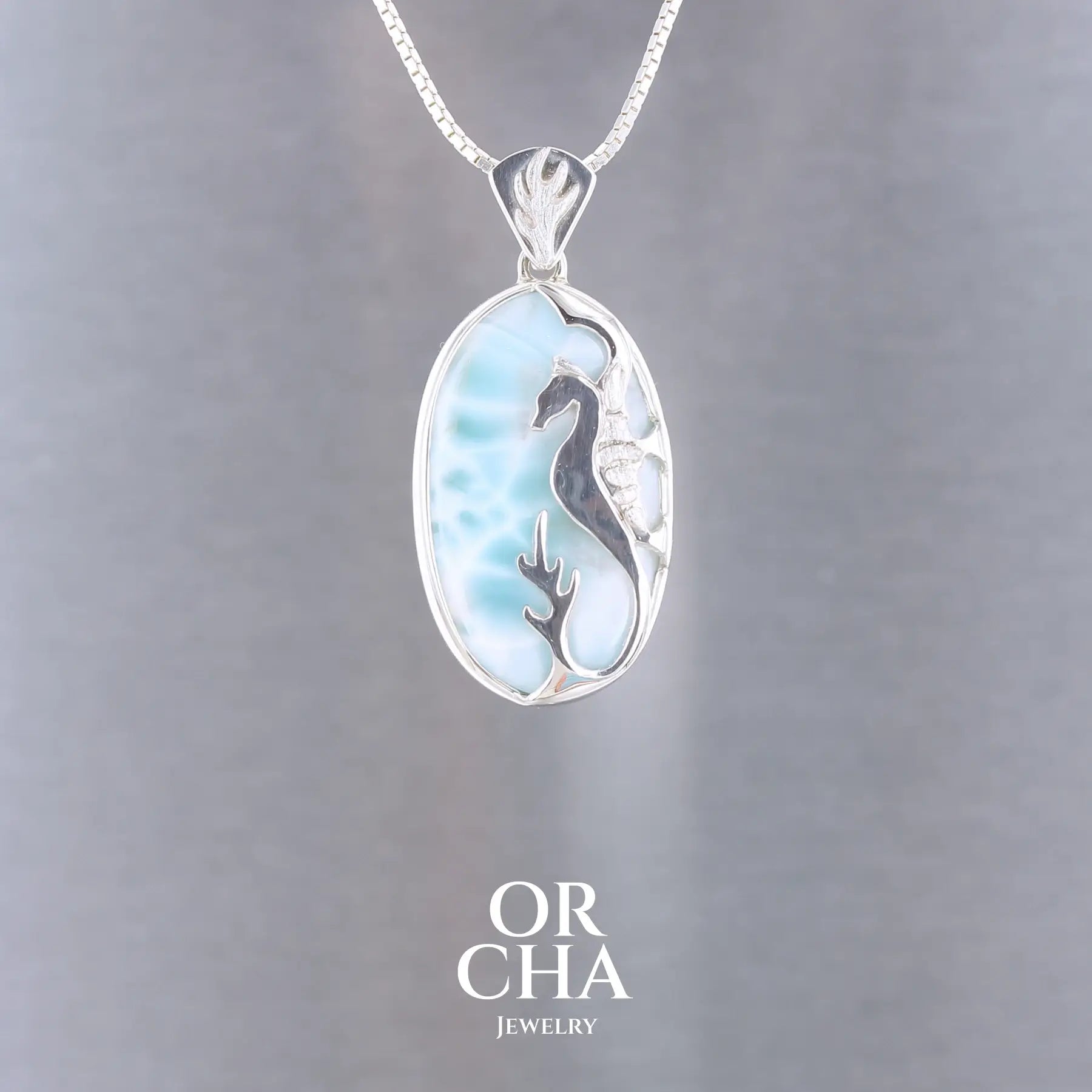 Pendentif artisanal en argent sterling 925 présentant un cabochon ovale de larimar bleu ciel aux nuances turquoise et blanches. Sur la pierre, un hippocampe en argent contraste élégamment avec les tons océaniques du larimar. L'ensemble évoque la sérénité des fonds marins caribéens. Bijoux unique, éthique et durable présenté dans un coffret de notre marque, prêt à offrir. Livraison offerte, certificat d'authenticité, service client.