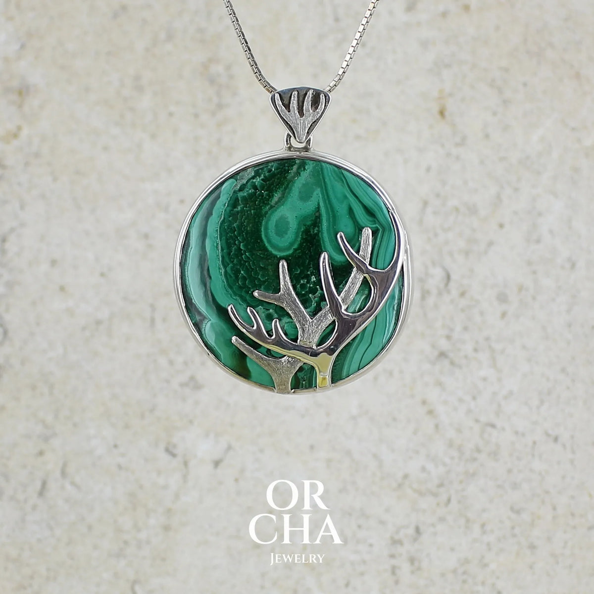 Pendentif de créateur en argent massif, où s'illustre des bois de cerf sculpté en argent massif et serti sur un cabochon de Malachite. Pierre au superbes nuances de verts, pierre opaque naturelle de forme ronde. Bijoux unique réalisé par orchajewelry