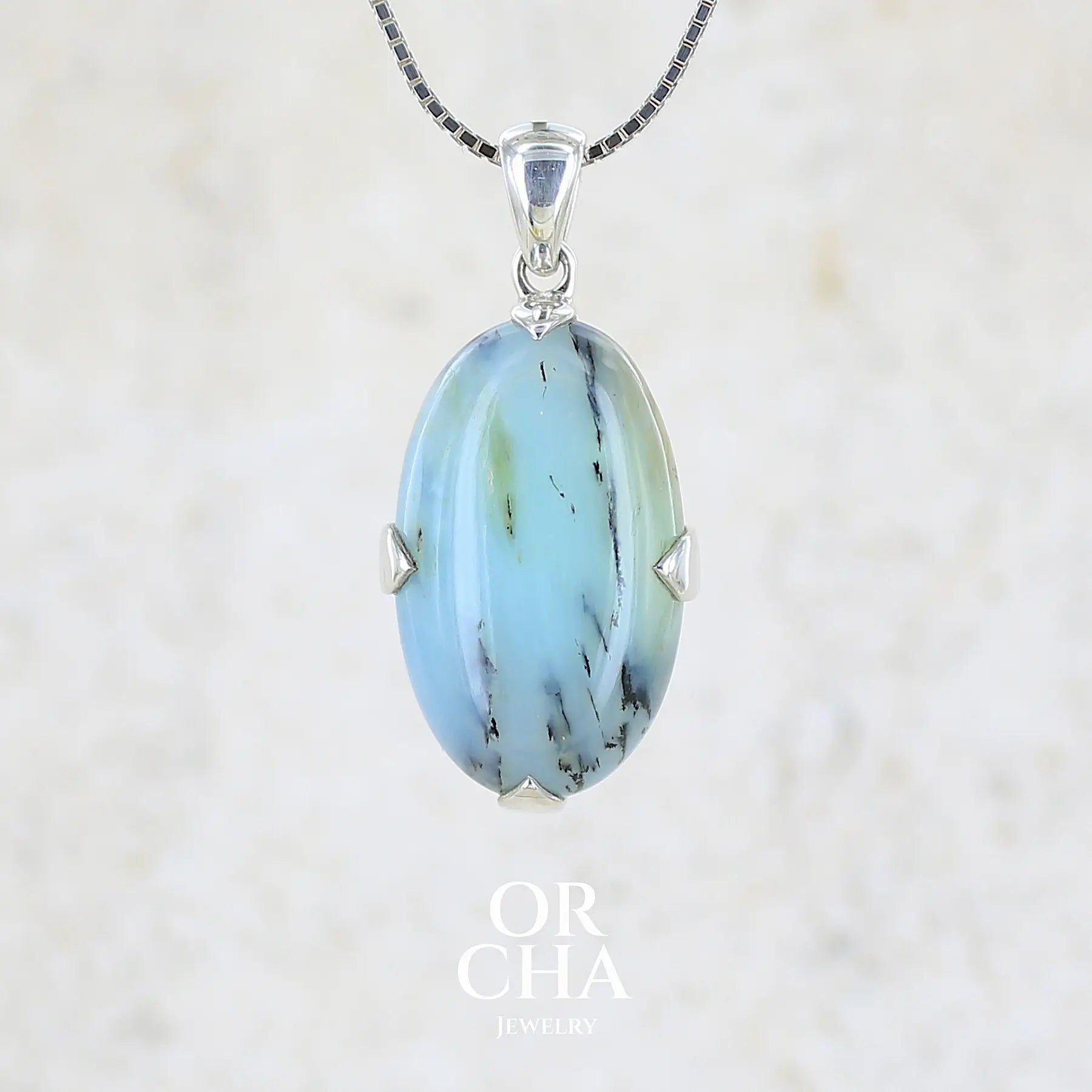 Pendentif en argent massif, sertie d'un cabochon ovale d'opale bleue du Pérou de couleur bleu laiteux à inclusions de dendrites noires. Pierre opaque et translucide. Bijoux unique, éthique et durable présenté dans un coffret de notre marque, prêt à offrir. Livraison offerte, certificat d'authenticité, service client.
