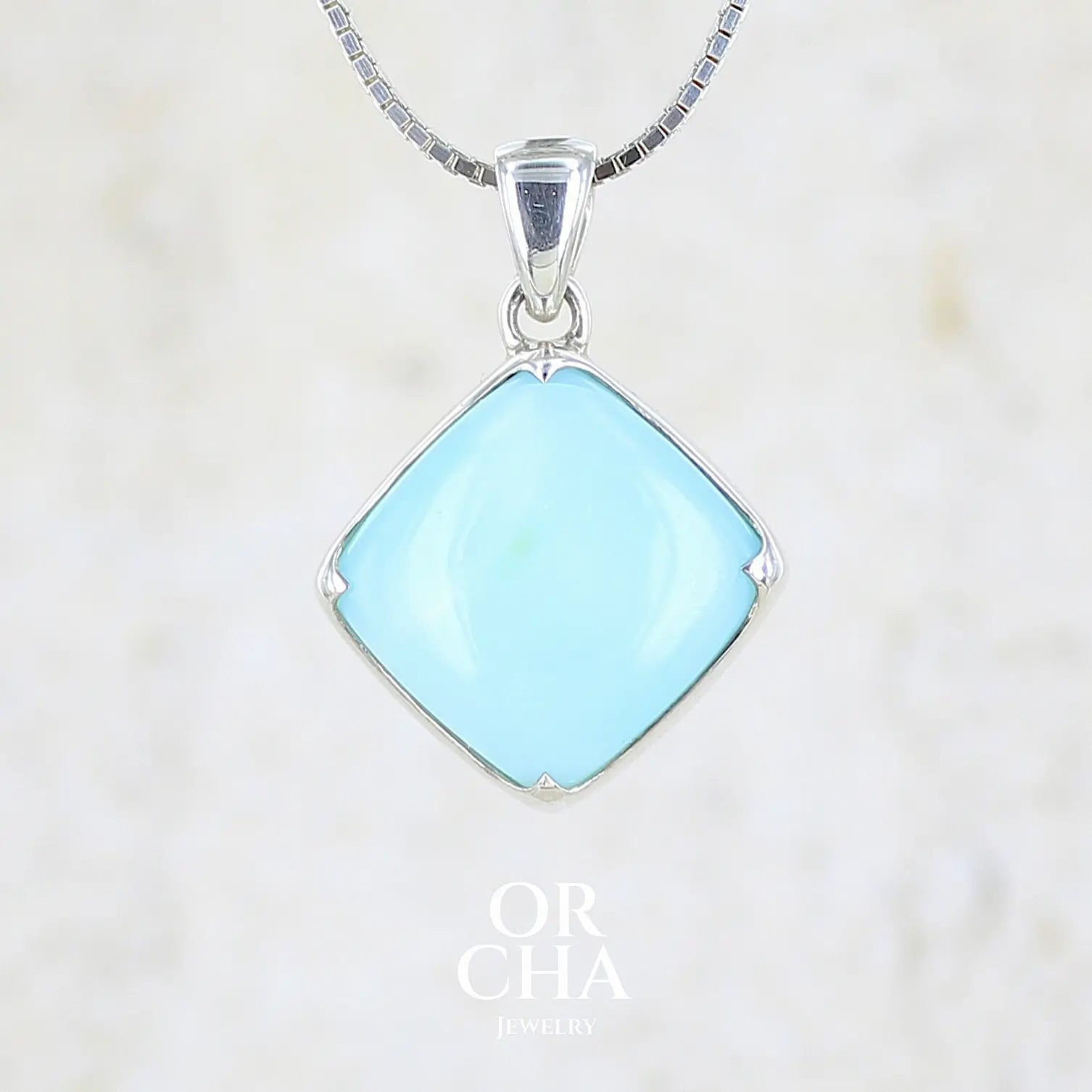 Pendentif en argent massif, sertie d'un cabochon d'opale bleue du Pérou de couleur bleu ciel clair. Pierre de forme carrée. Pierre opaque. Bijoux unique, éthique et durable présenté dans un coffret de notre marque, prêt à offrir. Livraison offerte, certificat d'authenticité, service client.