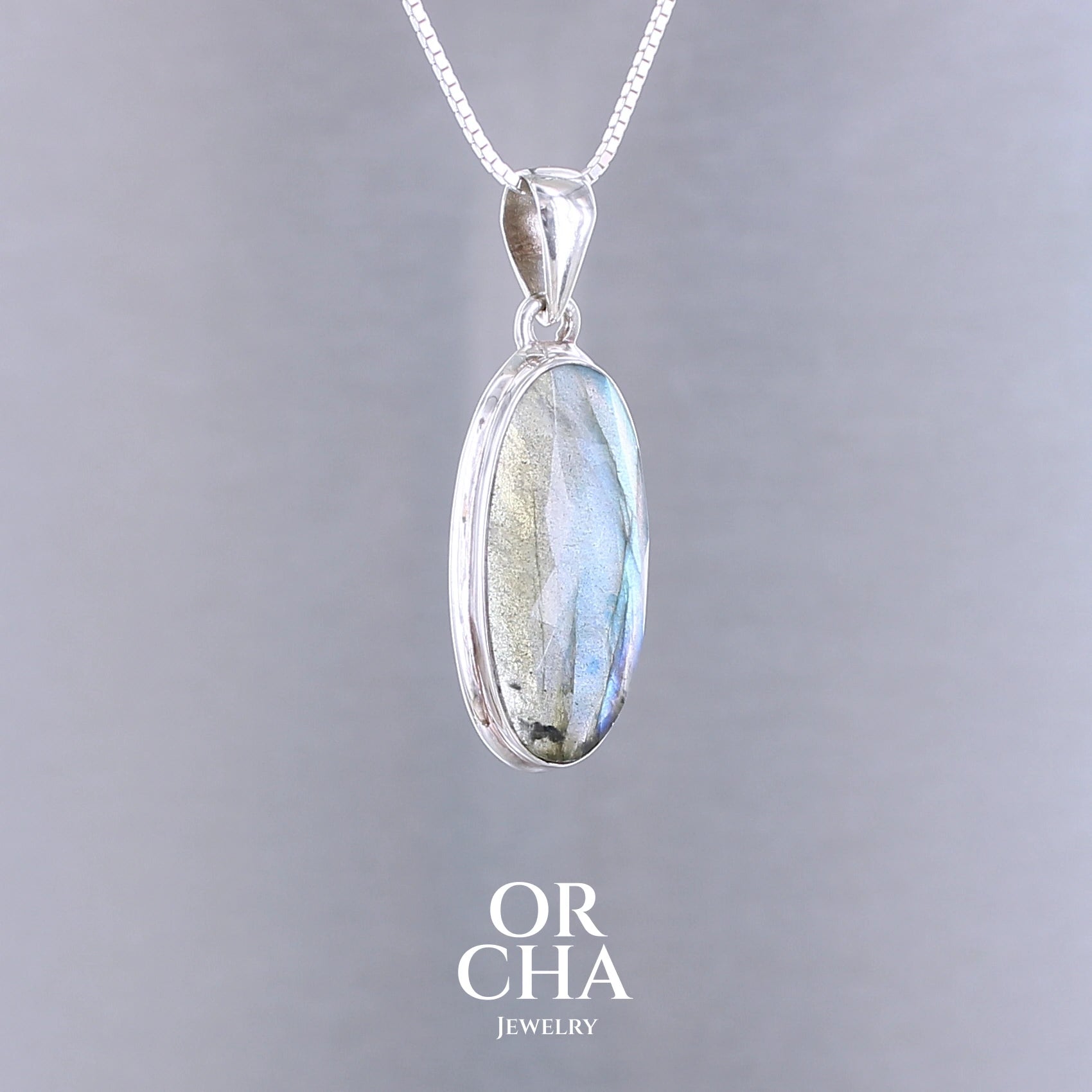 Pendentif pour femme en argent massif sertie d'une labradorite aux reflets bleus clairs selon la lumière. Pierre facettée naturelle translucide présentant des inclusions fréquents sur ce type de pierre. Bijoux unique, éthique et durable présenté dans un coffret de notre marque, prêt à offrir. Livraison offerte, certificat d'authenticité, service client.