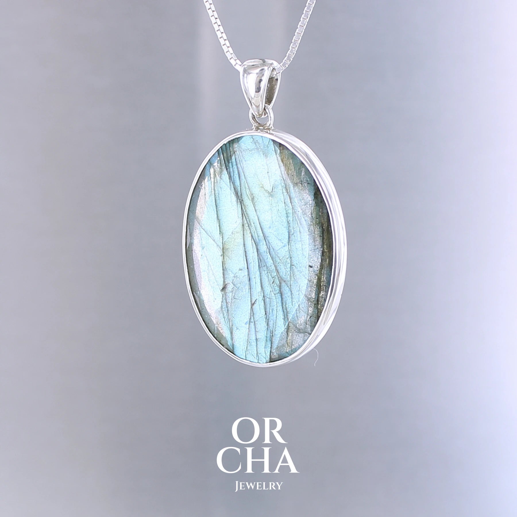 Pendentif ovale pour femme en argent massif serti d'une labradorite aux reflets bleus clairs, bleu vert selon la lumière. Pierre facettée naturelle translucide présentant des inclusions fréquents sur ce type de pierre. Bijoux unique, éthique et durable présenté dans un coffret de notre marque, prêt à offrir. Livraison offerte, certificat d'authenticité, service client.
