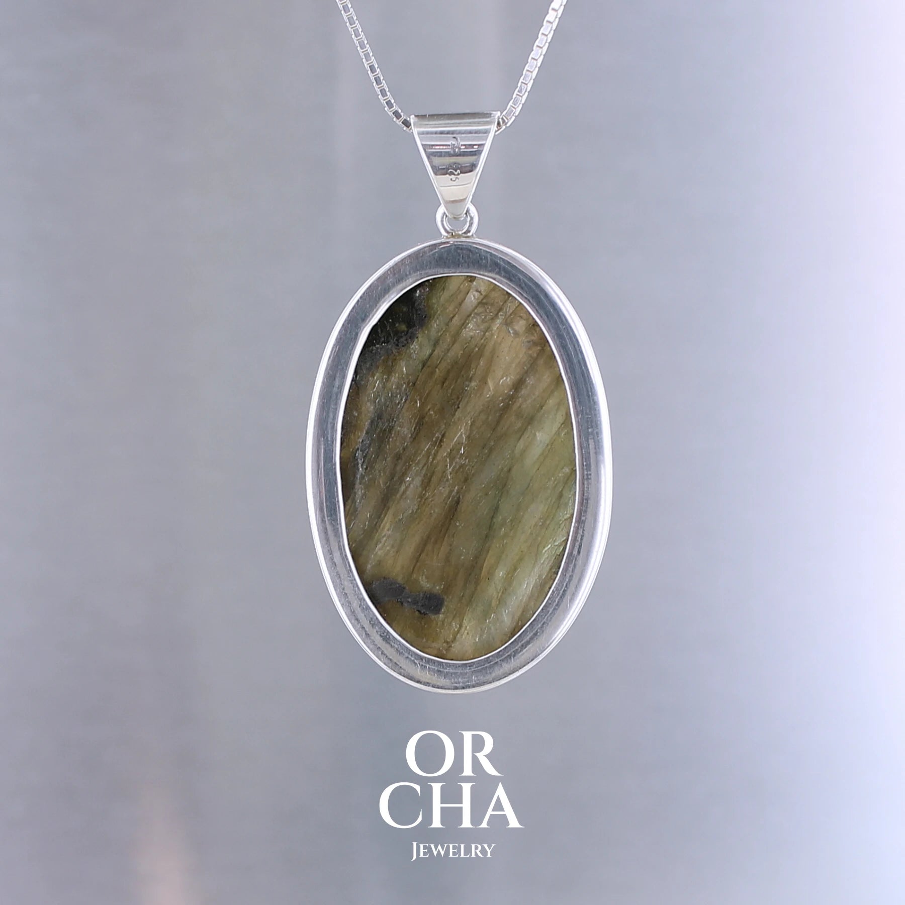 Pendentif pour femme en argent massif sertie d'une labradorite aux reflets bleu turquoise selon la lumière. Pierre cabochon naturelle translucide présentant des inclusions fréquents sur ce type de pierre. Bijoux unique, éthique et durable présenté dans un coffret de notre marque, prêt à offrir. Livraison offerte, certificat d'authenticité, service client.