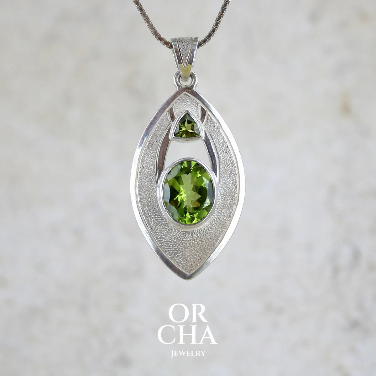Pendentif pour femme en argent massif serti d'un péridot de couleur vert olive doré intense. Pierre taillée, de forme ovale, transparente propre à l'oeil. Bijou unique réalisé par Orchajewelry
