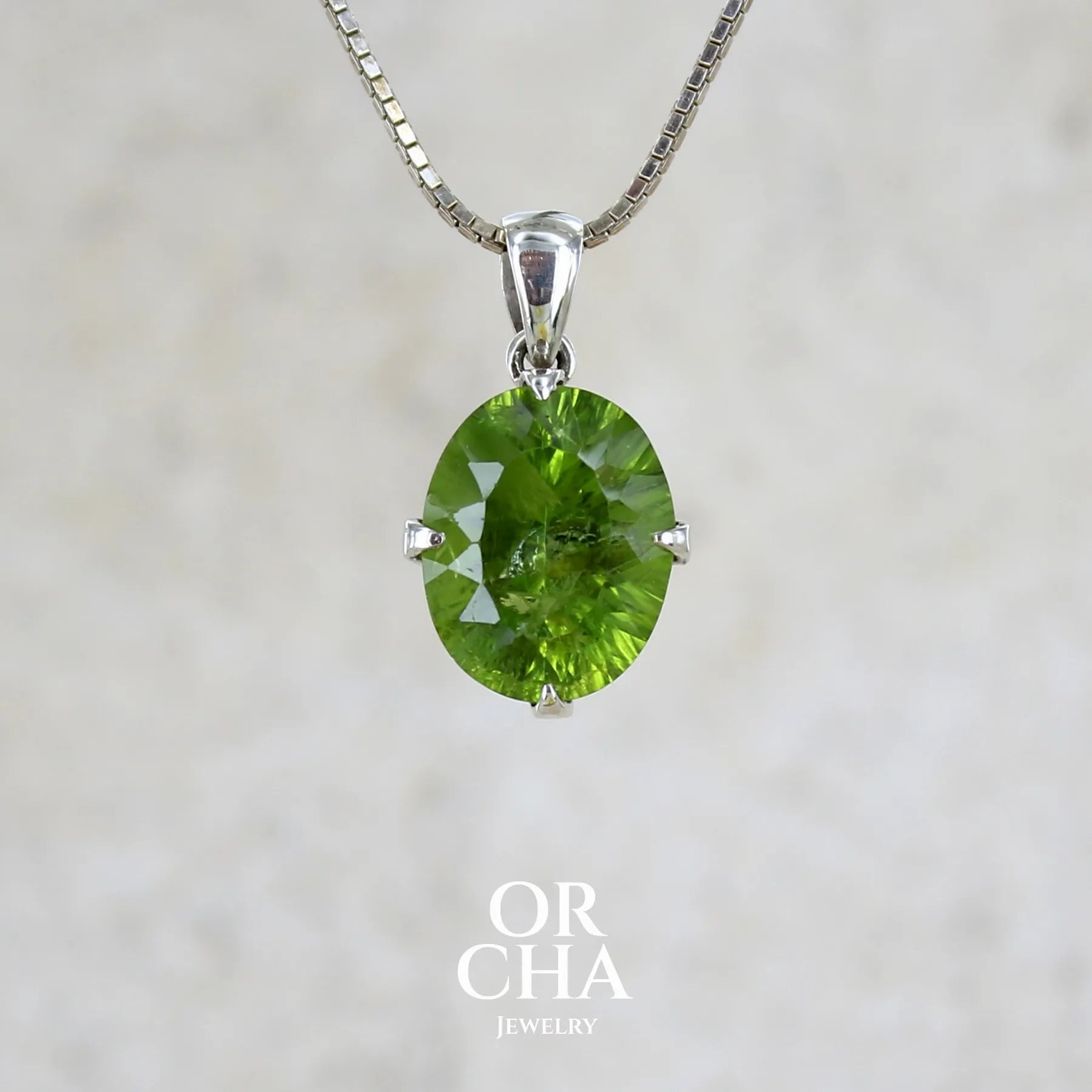 Pendentif pour femme en argent massif serti d'un péridot de couleur vert olive doré intense. Pierre taillée "laser cut", de forme ovale, transparente présentant de nombreuses inclusions. Bijou unique réalisé par Orchajewelry