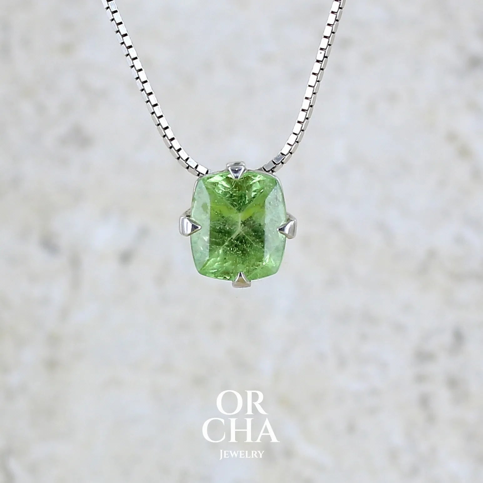 Collier solitaire pour femme en argent massif sertie d'un Péridot de couleur vert pastel anisé. Pierre facettée de forme carrée, qualité transparente présentant des inclusions. Pendentif monté sur une chaine en argent sterling de type maille miroir de 1,3 mm d'épaisseur et de 40cm de longueur. Bijoux unique réalisé par Orchajewelry