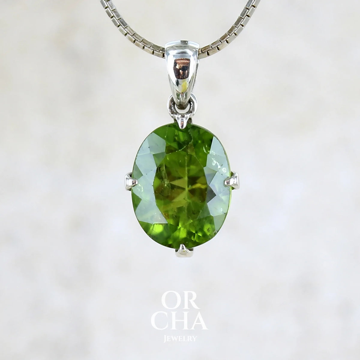 pendentif pour femme en argent massif serti d'un Péridot de couleur vert olive doré profond et intense . Pierre taillée transparente présentant des inclusions, de forme ovale. Bijoux unique par Orchajewelry
