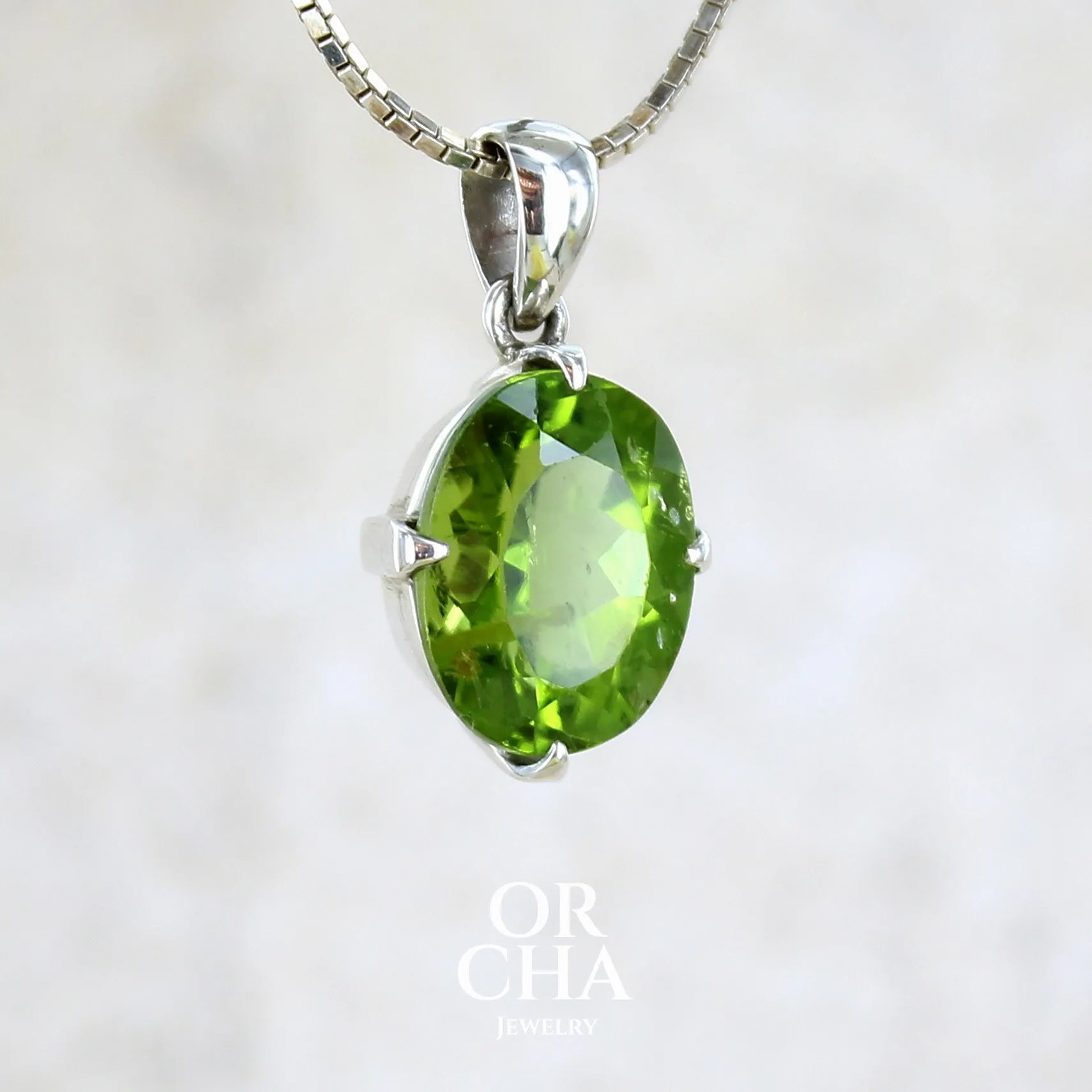 pendentif pour femme en argent massif serti d'un Péridot de couleur vert olive doré profond et intense . Pierre taillée transparente présentant des inclusions, de forme ovale. Bijoux unique par Orchajewelry