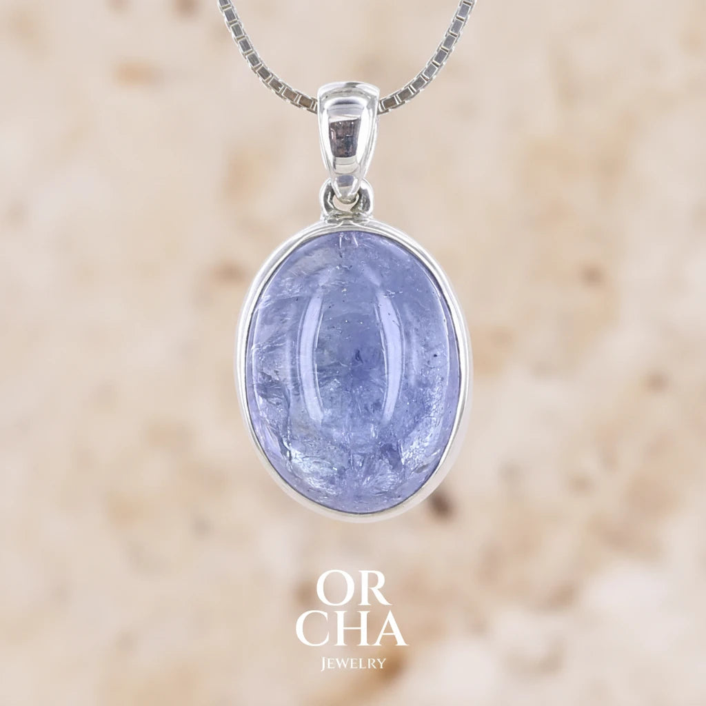 pendentif pour femme en argent massif serti d'un cabochon de Tanzanite de couleur bleu lavande. Pierre transparente présentant des inclusions. Pierre ayant subit un traitement de chauffe, traitement admis et fréquent en gemmologie pour ce type de pierre . Bijoux unique, éthique et durable présenté dans un coffret de notre marque, prêt à offrir. Livraison offerte, certificat d'authenticité, service client.