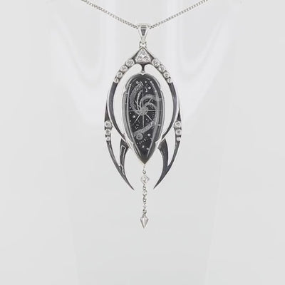 Pendentif luxueux en argent massif 925 présente un cristal de roche gravé en négatif d'une galaxie, sublimé par une tranche d'onyx noir créant un contraste saisissant. La monture en argent massif, aux lignes fluides évoquant le mouvement cosmique, enveloppe délicatement la pierre centrale.Des topazes blanches étincelantes, serties avec précision, illuminent cette création céleste comme des étoiles dans la nuit.Bijoux présenté dans un coffret de notre marque.Livraison offerte, certificat d'authenticité