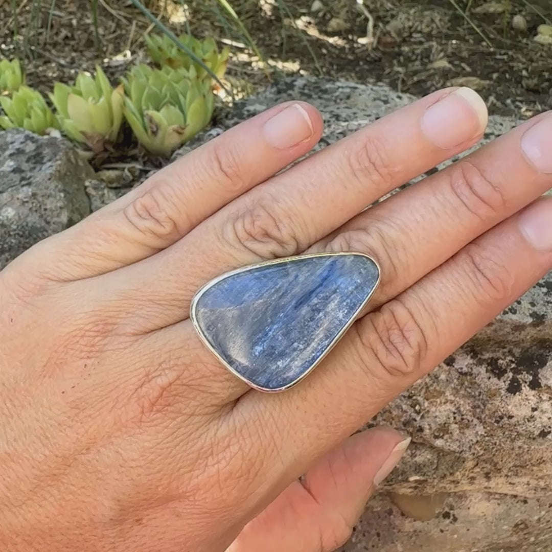 Bague longue et imposante pour femme en argent massif, sertie d'un cabochon de cyanite de couleur bleu jean nacré. Pierre taillée en forme de triangle de qualité translucide. Bijou unique réalisée en taille 58 par Orchajewelry