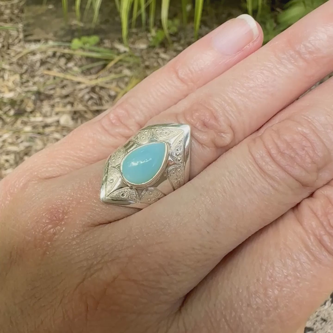 Bague pour femme en argent massif sculptées d'étoiles et autres corps célestes sertie d'une Opale bleue du Pérou. Pierre cabochon en forme de goutte, pierre naturelle de couleur bleu ciel ciel, bleu turquoise. Pierre naturelle de qualité opaque. Taille 51. Bijoux unique, éthique et durable présenté dans un coffret de notre marque, prêt à offrir. Livraison offerte, certificat d'authenticité, service client.