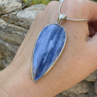 Pendentif en argent massif serti d'un cabochon de cyanite de couleur bleue jeans nacré. Pierre de qualité translucide taillée en forme de goutte inversée comportant des inclusions. Bijoux unique par Orchajewelry