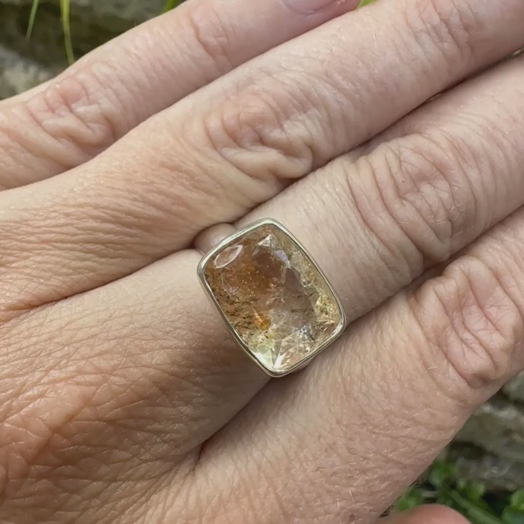 vidéo d'une Bague cocktail pour femme en argent massif sertie d'une pierre de soleil oranges de très belle qualité, pierre transparente avec inclusions scintillantes d'hématites.Pierre naturelle facettée de forme rectangulaire. Tailles 54. Bijoux unique, éthique et durable présenté dans un coffret de notre marque, prêt à offrir. Livraison offerte, certificat d'authenticité, service client.