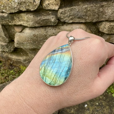 Pendentif pour femme en argent massif sertie d'une labradorite aux reflets bleus, bronzes et multicolores selon la lumière. Pierre facettée naturelle translucide présentant des inclusions fréquents sur ce type de pierre. Bijoux unique, éthique et durable présenté dans un coffret de notre marque, prêt à offrir. Livraison offerte, certificat d'authenticité, service client.