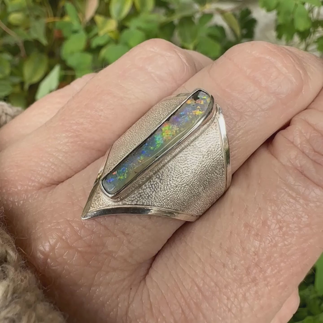 Bague plastron pour femme en argent massif 925 sertie d'une opale boulder aux feux multicolores. Cabochon d'opale massive naturelle, de qualité opaque. Bijoux unique réalisé en taille 59 par Orcha Jewelry.