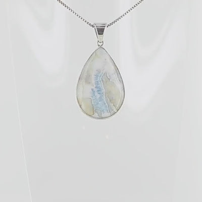 Pendentif pour femme en argent massif sertie d'une scheelite bleue. Pierre naturelle de couleur bleu, beige crème et blanc, de qualité opaque. Bijoux unique, éthique et durable présenté dans un coffret de notre marque, prêt à offrir. Livraison offerte, certificat d'authenticité, service client.