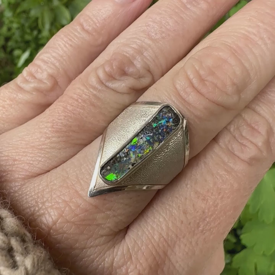 Bague pour femme en argent massif 925 sertie d'une opale boulder aux feux multicolores. Cabochon d'opale massive naturelle taillée en forme de rectangle.. Pierre de qualité opaque. Bague unique réalisée en taille 55 par Orcha Jewelry.