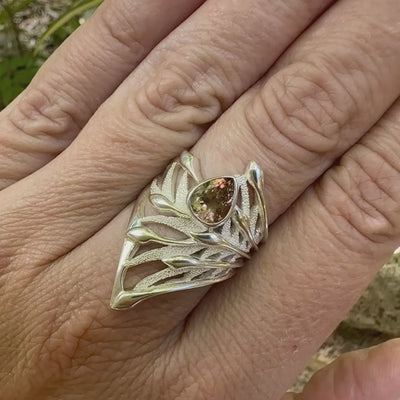 vidéo d'une grande Bague pour femme, feuillage tropicale travaillé en filigrane en argent massif, sertie d'une Tourmaline bicolore rose pêche et verte kaki. Pierre facettée en forme de goutte. Pierre incolore, très lumineuse et propre à l'oeil. Taille 56. Bijoux unique, éthique et durable présenté dans un coffret de notre marque, prêt à offrir. Livraison offerte, certificat d'authenticité, service client.