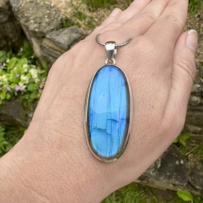 Pendentif ovale pour femme en argent massif sertie d'une labradorite aux reflets bleus électrique. Pierre cabochon naturelle translucide présentant des inclusions fréquents sur ce type de pierre. Bijoux unique, éthique et durable présenté dans un coffret de notre marque, prêt à offrir. Livraison offerte, certificat d'authenticité, service client.