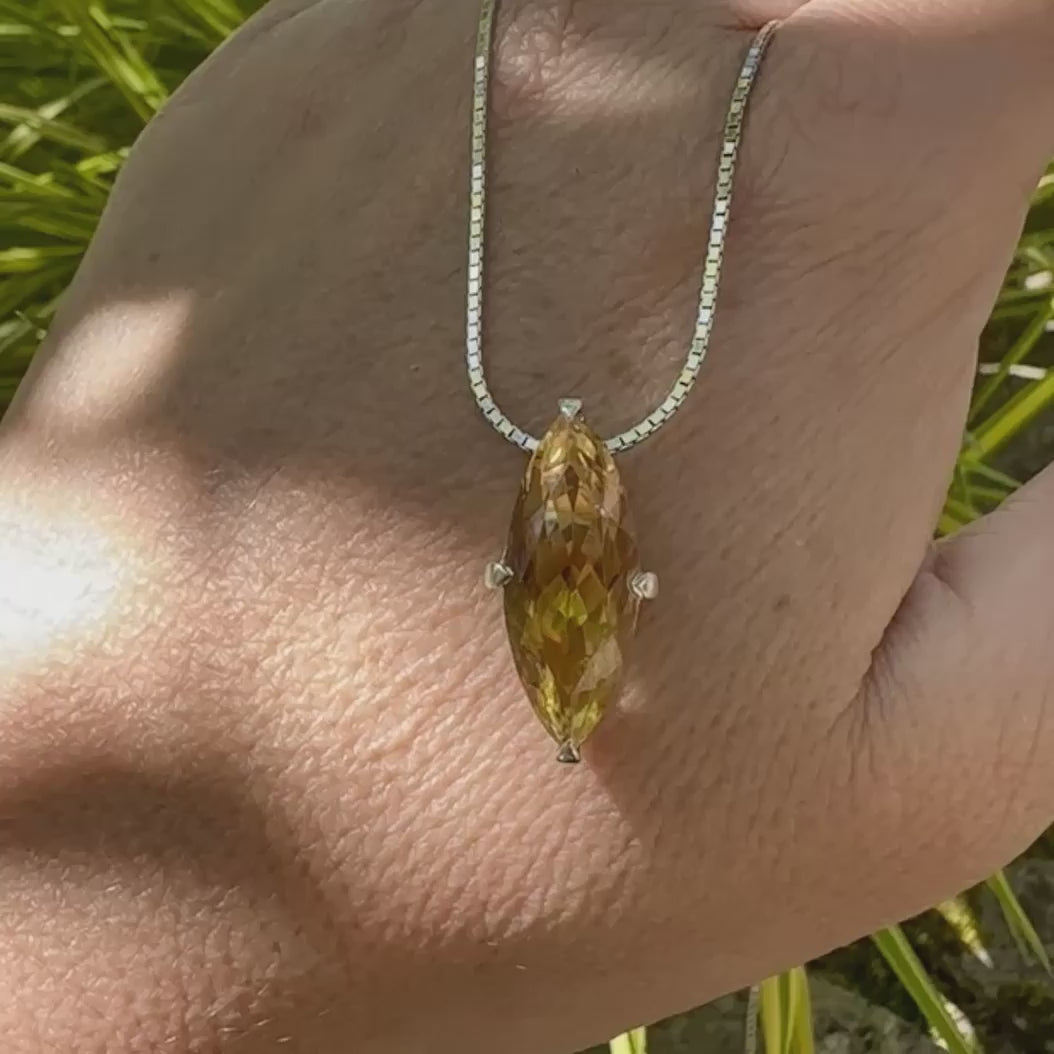 video d'un collier solitaire pour femme en argent massif sertie d'une Citrine. Pierre facettée en forme de marquise de qualité transparente, propre à l'oeil. Pierre naturelle de couleur jaune clair à jaune foncé. Pendentif monté sur une chaine en argent sterling de type maille miroir de 1,3 mm d'épaisseur et de 40 cm de longueur. Bijoux unique, éthique et durable présenté dans un coffret de notre marque, prêt à offrir. Livraison offerte, certificat d'authenticité, service client.