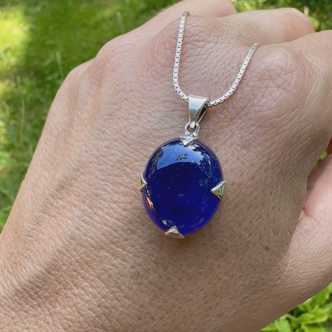 vidéo d'un pendentif pour femme en argent massif serti d'un cabochon de Tanzanite de couleur bleu lavande foncé profond et intense . Pierre transparente présentant des inclusions. Pierre ayant subit un traitement de chauffe, traitement admis et fréquent en gemmologie pour ce type de pierre . Bijoux unique, éthique et durable présenté dans un coffret de notre marque, prêt à offrir. Livraison offerte, certificat d'authenticité, service client.
