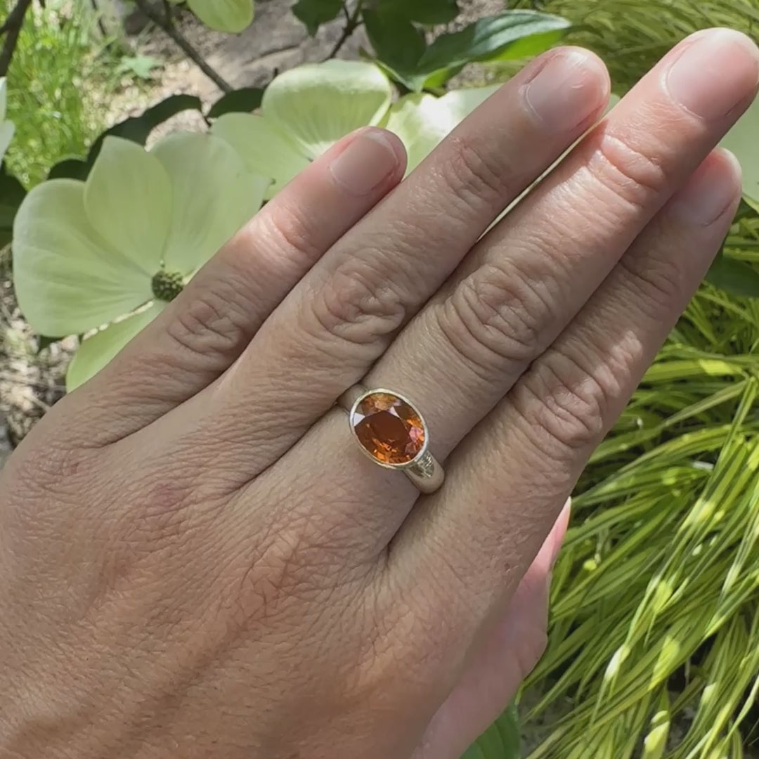 vidéo d'une bague cocktail pour femme en argent massif sertie d'un Grenat Spessartite. Pierre facettée de forme ovale de qualité transparente, propre à l'oeil. Pierre naturelle de couleur orange intense, ce Grenat est également appelé Grenat "Fanta" en rapport à la couleur saturé du célèbre soda. Tailles 58.5.  Bijoux unique, éthique et durable présenté dans un coffret de notre marque, prêt à offrir. Livraison offerte, certificat d'authenticité, service client.