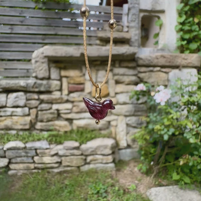 Collier pour femme orné d'une tourmaline rouge violacé sculptée à la main en 3 dimensions en forme d'oiseau sertie en or 18k. Le pendentif est monté sur un collier corde doré scintillant, les apprêts utilisé sont en Gold filled ( or laminé ). Longueur ajustable de 40 cm à 45 cm. Bijoux unique, éthique et durable présenté dans un coffret de notre marque, prêt à offrir. Livraison offerte, certificat d'authenticité, service client.
