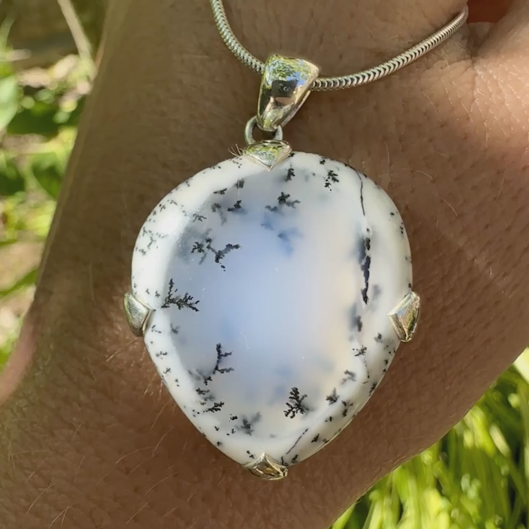 Pendentif pour femme en argent massif sertie d'un cabochon en forme de goutte inversée d'agate dendritique de couleur blanc pur et noir. Pierre opaque à translucide à inclusions paysages de dendrites de manganèse noires contrastées. Bijou unique réalisée par Orchajewelry