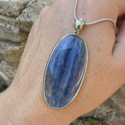 Pendentif en argent massif serti d'un cabochon ovale de cyanite de couleur bleue jeans nacré. Pierre de qualité translucide comportant des inclusions.Bijoux unique par Orcha Jewelry
