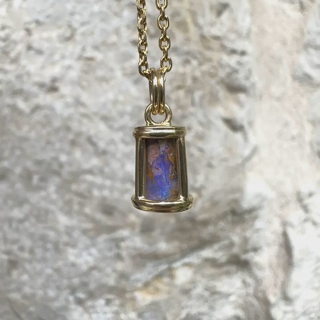 Pendentif pour femme en or jaune massif 14k serti d'une opale pipe aux feux  multicolores à dominantes bleu et violet. Specimen cylindrique, sertissage cage, opale rarement proposé en bijouterie. Bijou unique par par Orchajewelry
