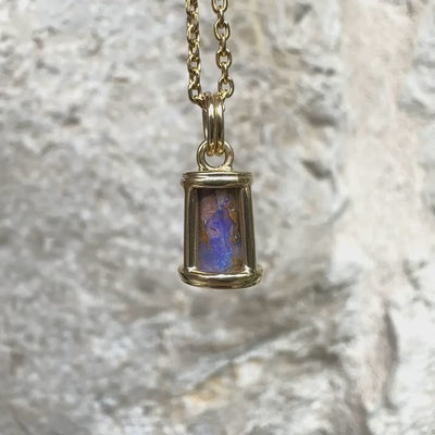 Pendentif pour femme en or jaune massif 14k serti d'une opale pipe aux feux  multicolores à dominantes bleu et violet. Specimen cylindrique, sertissage cage, opale rarement proposé en bijouterie. Bijou unique par par Orchajewelry