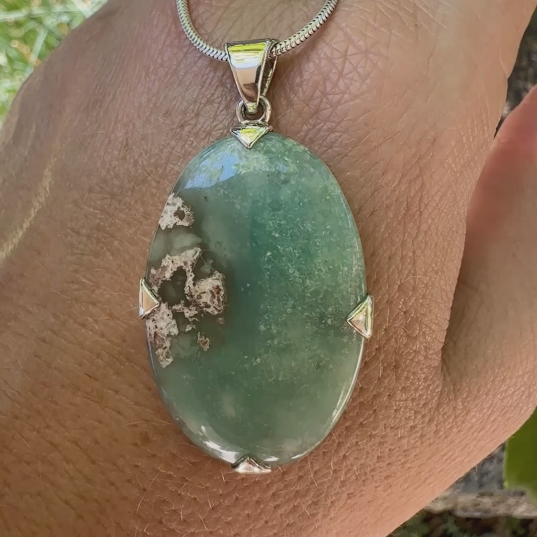 Pendentif ovale en argent massif, serti d'un cabochon de calcédoine de couleur bleue verte. Pierre de qualité translucide comportant des inclusions paysages blanches. Bijoux unique par Orcha Jewelry