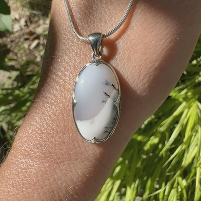 Pendentif pour femme en argent massif sertie d'un cabochon de forme ovale d'agate dendritique de couleur blanc pur et noir. Pierre opaque à translucide à inclusions paysages de dendrites de manganèse noires contrastées. Bijou unique réalisé par Orchajewelry
