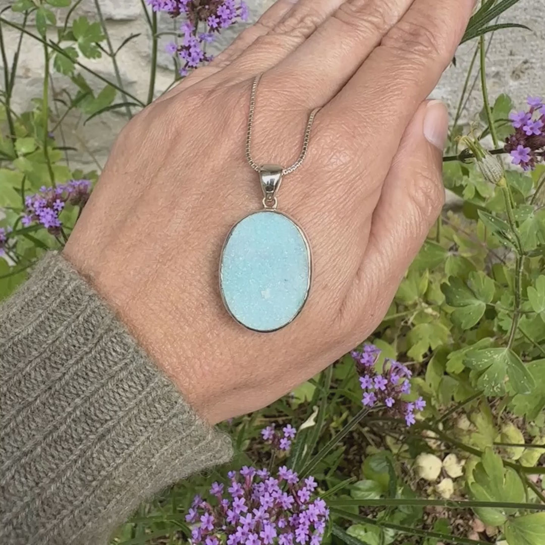 Pendentif pour femme en argent massif sertie d'un magnifique gemsilica druzy, chrysocolle silicifiée recouverte de fins cristaux de quartz scintillant. Pierre de qualité opaque taillée en tranche de forme ovale. Pierre naturelle originaire de République dominicaine du Congo de couleur bleu clair turquoise. pierre rare et unique
