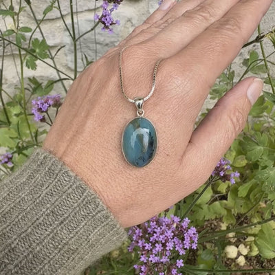 Pendentif en argent massif, sertie d'un cabochon ovale d'opale bleue du Pérou de couleur bleu laiteux foncé à inclusions de dendrites paysages noires et de roche mère marron. Pierre opaque et translucide. Bijoux unique, éthique et durable présenté dans un coffret de notre marque, prêt à offrir. Livraison offerte, certificat d'authenticité, service client.