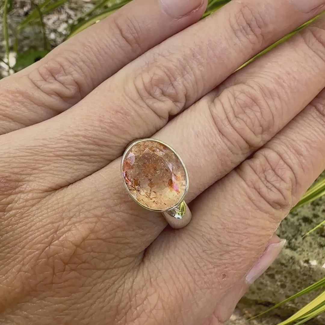 Bague cocktail pour femme en argent massif sertie d'une Pierre de soleil. Pierre ovale facettée de de couleur orange clair avec des inclusions scintillantes d'hématites. Pierre naturelle. Bijoux unique, réalisé en taille 60, éthique et durable présenté dans un coffret de notre marque, prêt à offrir. Livraison offerte, certificat d'authenticité, service client.