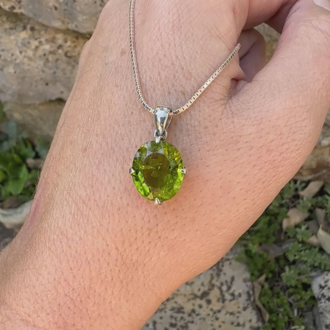 Pendentif pour femme en argent massif serti d'un péridot de couleur vert olive doré intense. Pierre taillée, de forme ovale, transparente présentant de nombreuse inclusions. Bijou unique réalisé par Orchajewelry