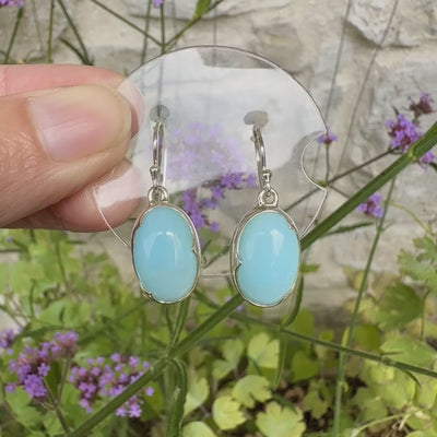 Boucles d'oreilles pendantes en argent massif serties d'opale bleue du Pérou. Pierres cabochon taillée en ovale de qualité opaque. Pierre naturelle de couleur bleu ciel. Bijoux unique, éthique et durable présenté dans un coffret de notre marque, prêt à offrir. Livraison offerte, certificat d'authenticité, service client.