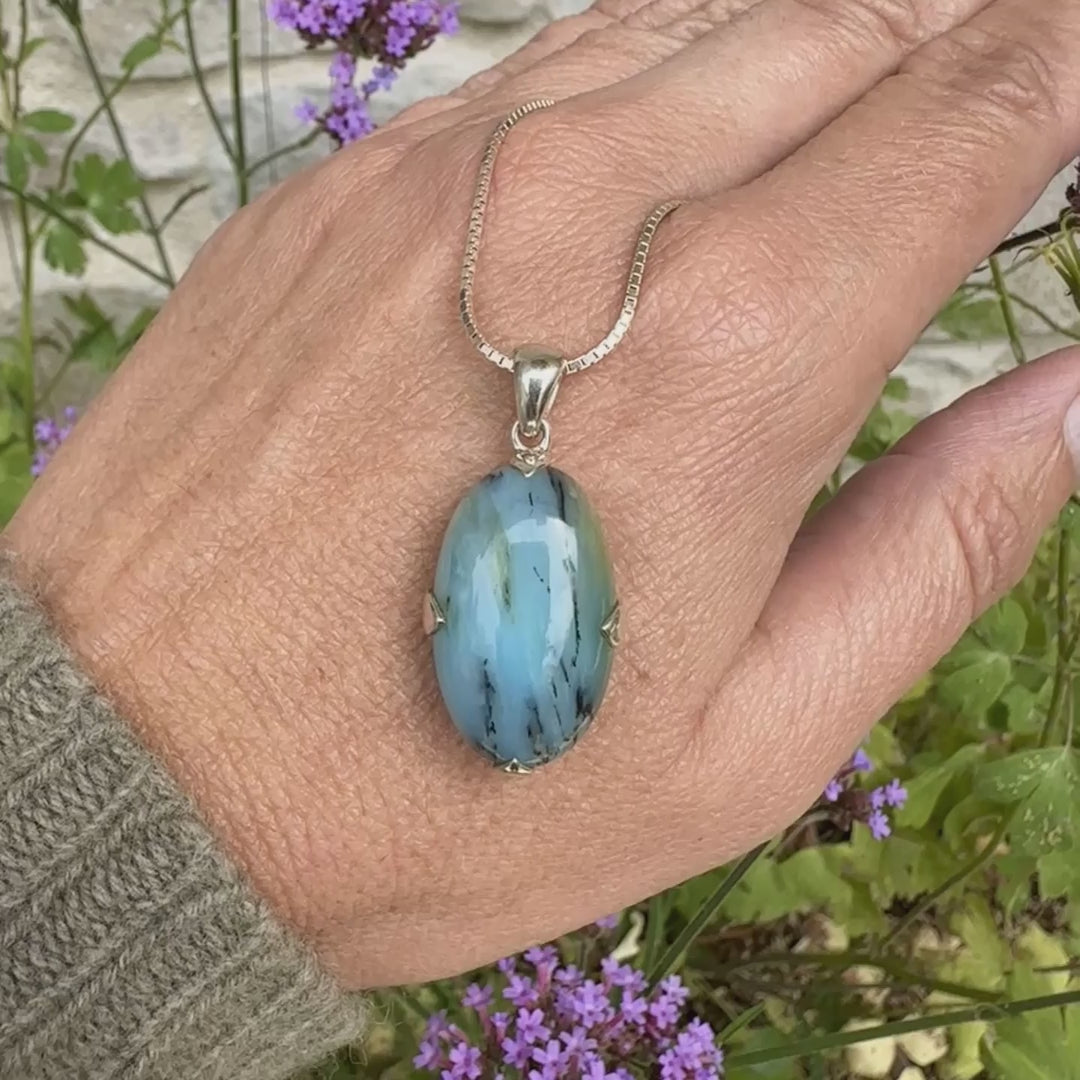 Pendentif en argent massif, sertie d'un cabochon ovale d'opale bleue du Pérou de couleur bleu laiteux à inclusions de dendrites noires. Pierre opaque et translucide. Bijoux unique, éthique et durable présenté dans un coffret de notre marque, prêt à offrir. Livraison offerte, certificat d'authenticité, service client.