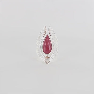 Vidéo d'une grande bague pour femme en argent massif sertie d'une Rhodonite. Pierre cabochon en forme de goutte, pierre naturelle de couleur rouge coquelicot. Pierre fine de qualité  opaque à translucide présentant des inclusions. Taille 59. Bijoux unique, éthique et durable présenté dans un coffret de notre marque, prêt à offrir. Livraison offerte, certificat d'authenticité, service client.