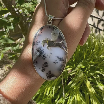 Pendentif en argent massif sertie d'un grand cabochon de forme ovale d'agate dendritique de couleur blanc pur et noir. Pierre opaque à translucide à inclusions paysages de dendrites de manganèse noires contrastées. Bijou unique illustré d'un cheval ailé réalisé par Orchajewelry