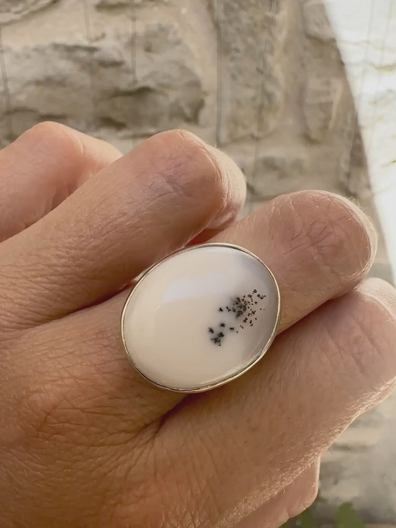 Bague pour femme en argent massif sertie d'un cabochon ovale d'agate dendritique de couleur blanc pur. Pierre opaque translucide à inclusions de dendrites de manganèse noires contrastées. Bijou unique réalisée en taille 56,5 par Orchajewelry