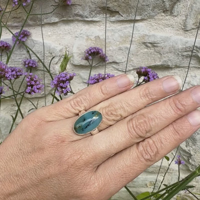 Bague en argent massif, sertie d'un cabochon ovale d'opale bleue du Pérou de couleur bleu foncé à inclusions de dendrites paysages noires et de roche mère jaune. Pierre naturelle opaque et translucide. Bijoux unique réalisé en taille 52 par Orcha jewelry