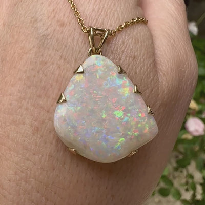 Pendentif pour femme en or jaune 18k serti d'une opale blanche de 17 carats aux feux multicolores. Pierre naturelle cabochon de forme irrégulière sertis  de griffes. A noter: présence de roche mère de couleur crème au dos de la pierre. Bijoux unique, éthique et durable présenté dans un coffret de notre marque, prêt à offrir. Livraison offerte, certificat d'authenticité, service client