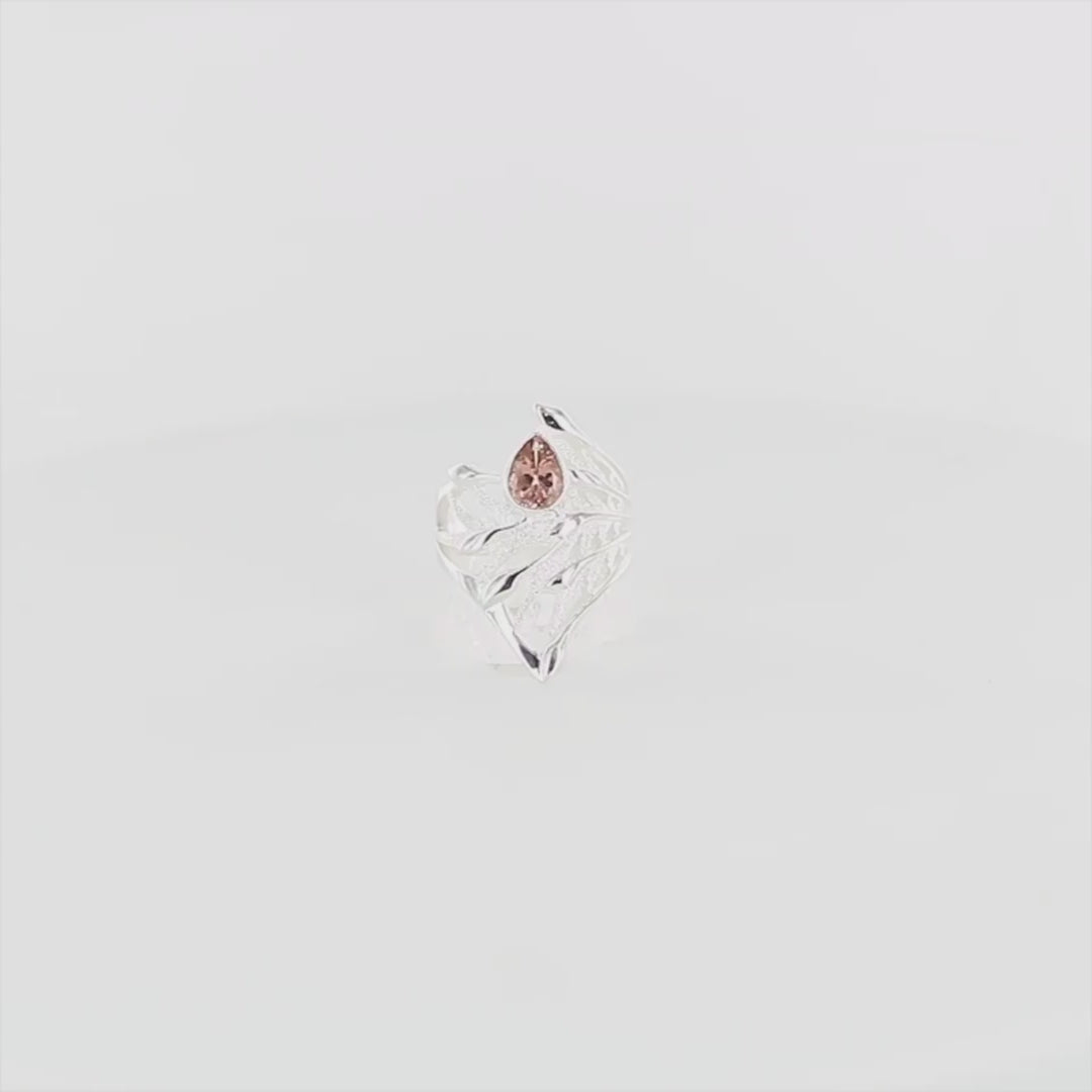 Bague en argent massif présentant un design sculptural évoquant un entrelacs une feuille stylisée, alternant entre surfaces lisses polies et zones texturées satinées. En son centre est sertie une tourmaline rose taille poire, lumineuse, aux reflets délicats. Bague réalisée en taille 54. Bijoux unique, éthique et durable présenté dans un coffret de notre marque, prêt à offrir. Livraison offerte, certificat d'authenticité, service client.